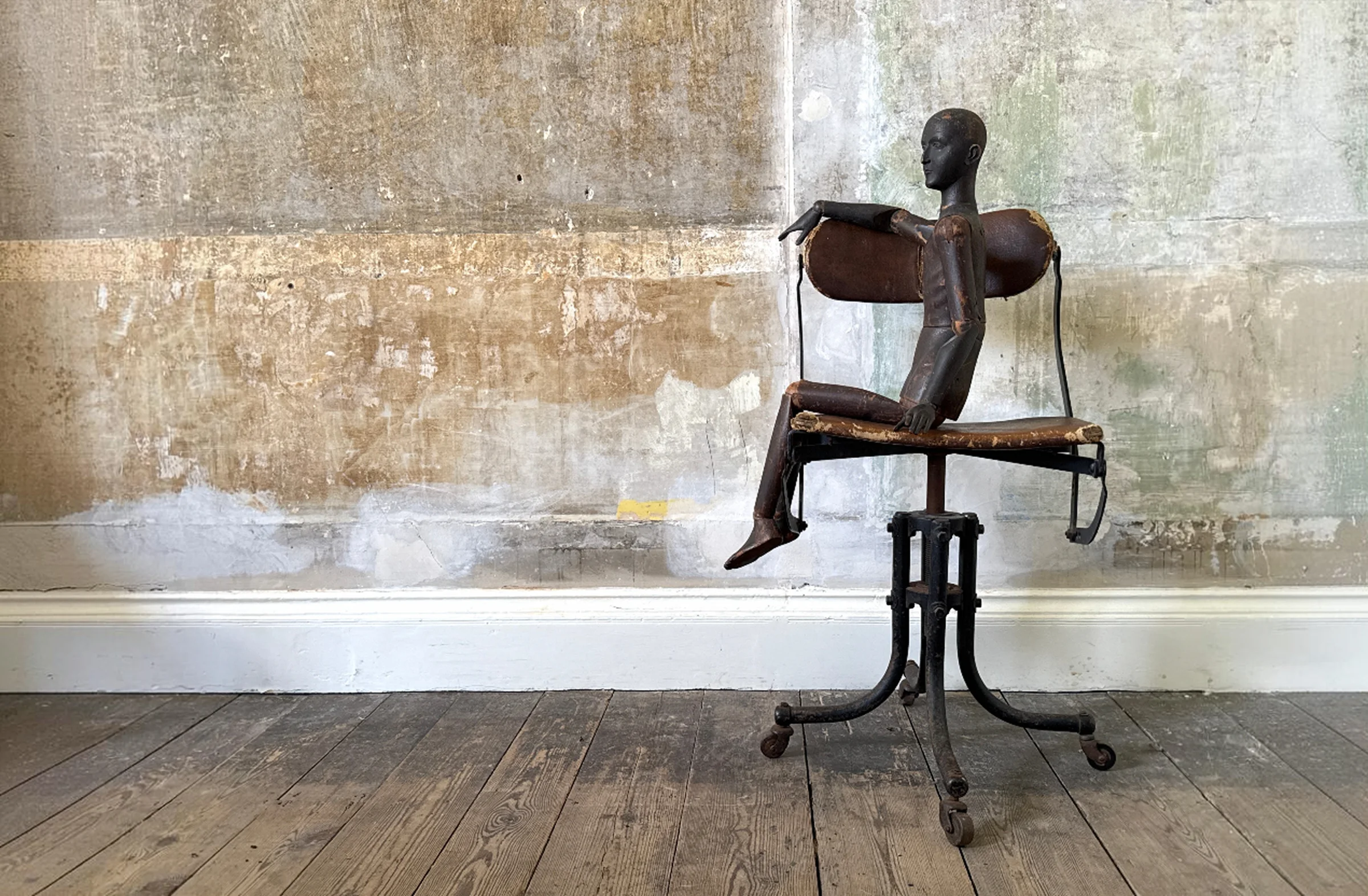 An antique mannequin seated on a leather chair in Drew Pritchard’s showroom